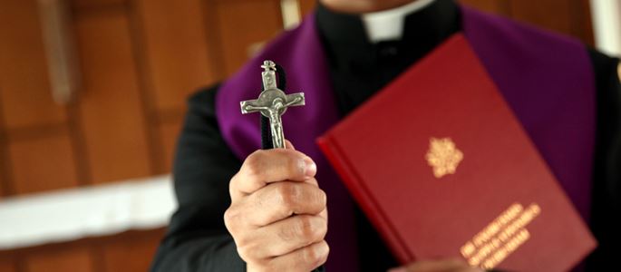 Ein Priester mit einem Kreuz in der Hand.