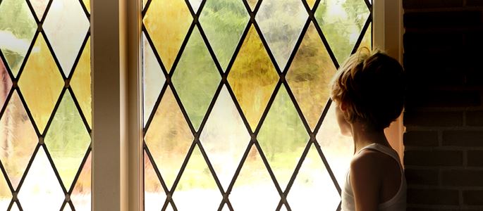 Ein Junge steht am Fenster in einer Kirche.