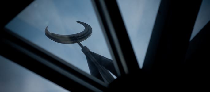 Blick auf einen Halbmond durch das Glasdach einer Moschee.