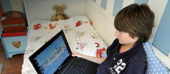 Der 11-jährige Max sitzt am Mittwoch (02.05.2012) in Düsseldorf mit seinem Laptop auf dem Bett.